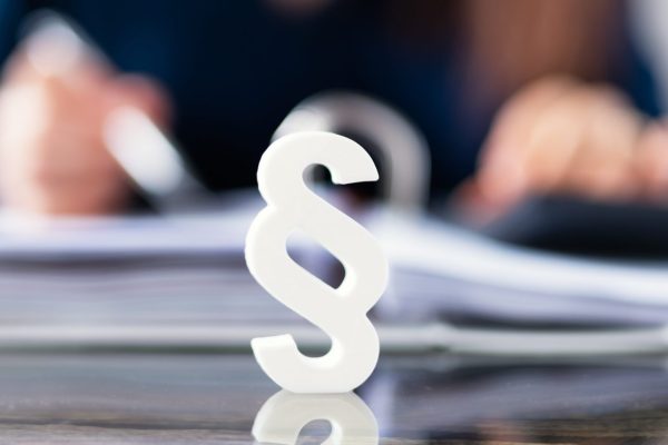 Close-up Of A Red Paragraph Symbol In Front Of Person Working At Workplace